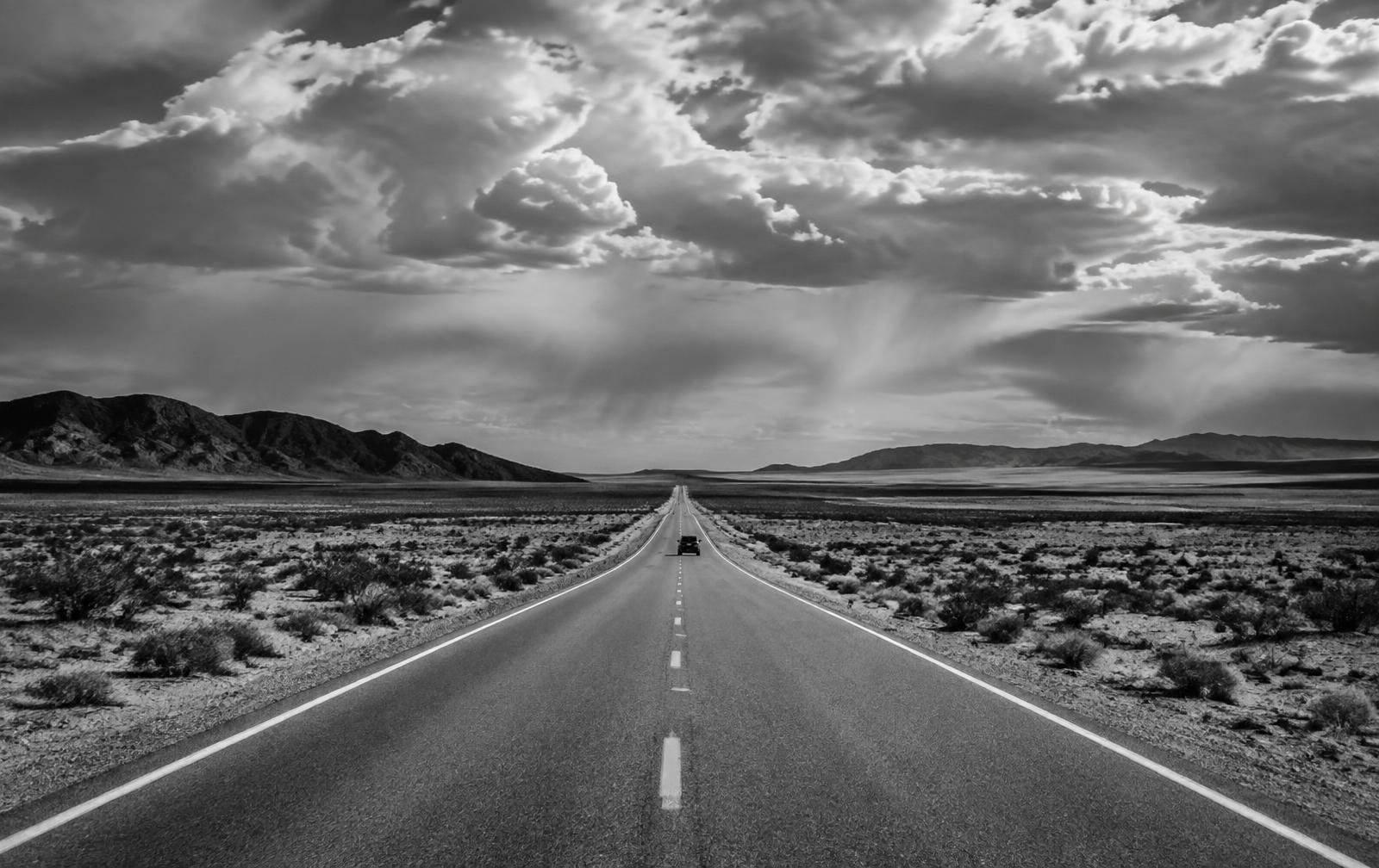 Aerial view of a straight desert road under dramatic clouds